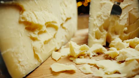 medium hard cheese head parmesan on wooden board, with cheese parmesan knifes. slide shot