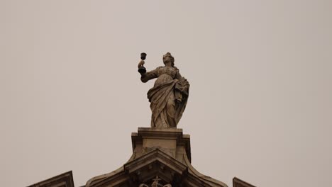 a stone statue atop historic architecture in porto, portugal. low angle shot
