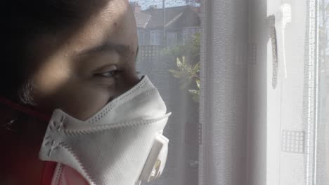 Asian-Bangladeshi-Child-Wearing-FFP-Three-Mask-Indoors-Looking-Through-Curtains