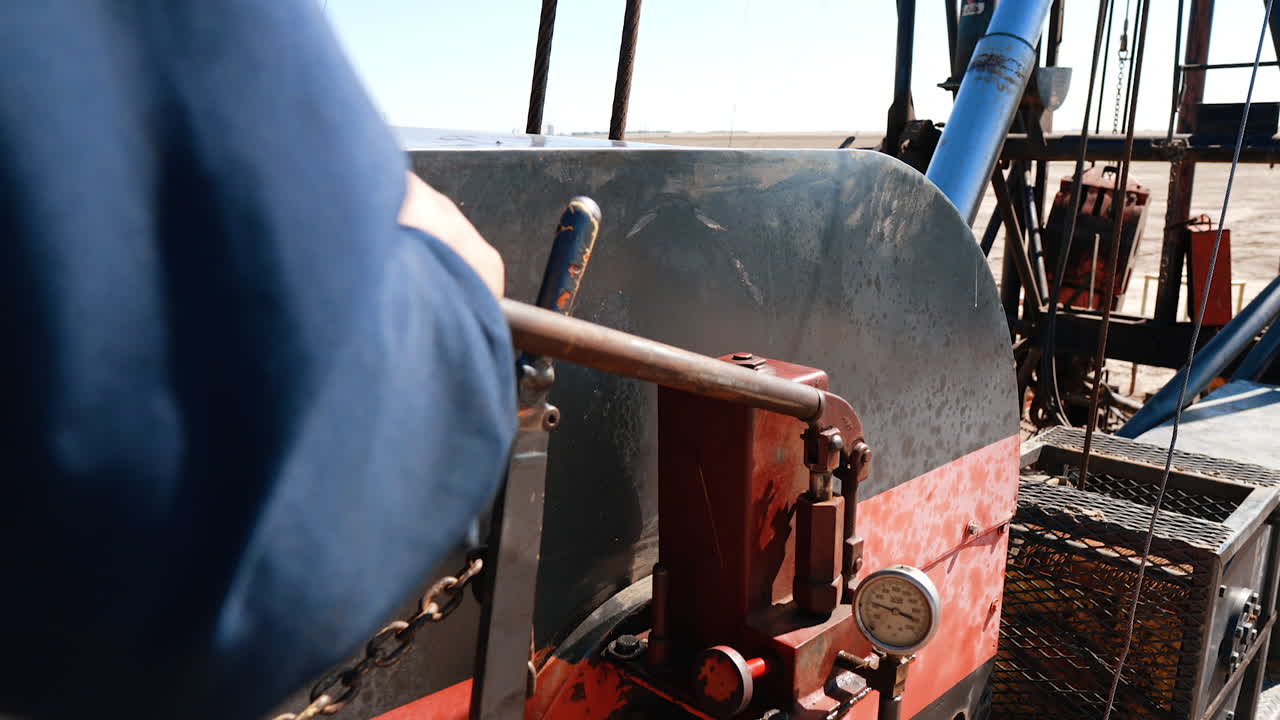 Unrecognized man operating drilling equipment. Worker pulls the lever of the machine pumping oil or gas.