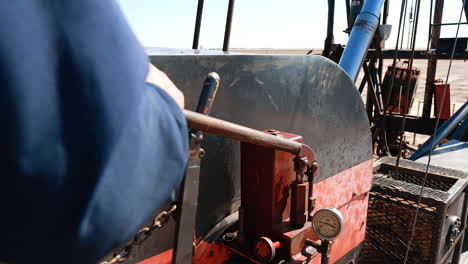 unrecognized man operating drilling equipment. worker pulls the lever of the machine pumping oil or gas.