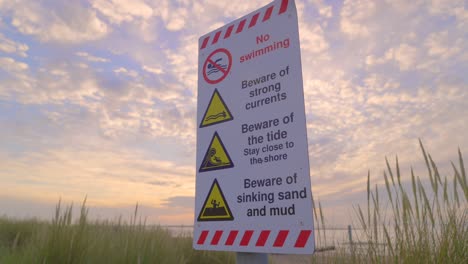 slow approach to warning sign at seaside at sunset