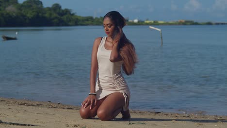 in her beach dress, a young girl embraces the joy of a sunny day on a caribbean beach kneel in the sand