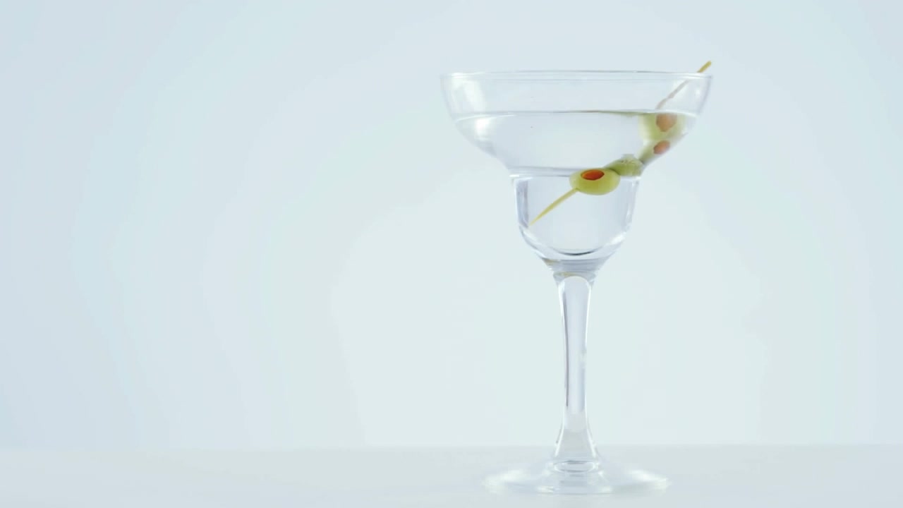 Animazione di puntini rossi che si muovono su un bicchiere da cocktail con olive su sfondo bianco.