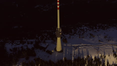 aerial tracking shot of big broadcast tower at sunset on the snowy mountain hornisgrinde in the black forest