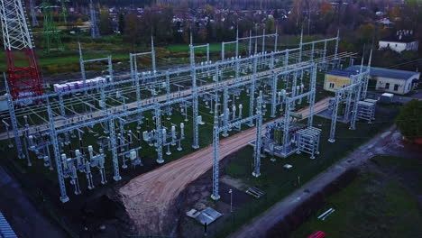 tilting drone shot over a high-voltage distribution site on the edge of a village