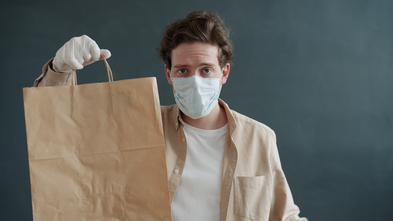 Delivery Person with Mask and Gloves Holding Paper Bag