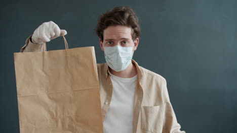 delivery person with mask and gloves holding paper bag