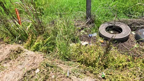 old tires littered along grassy roadside fence