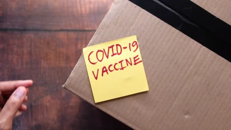 hands handling a box labeled covid-19 vaccine