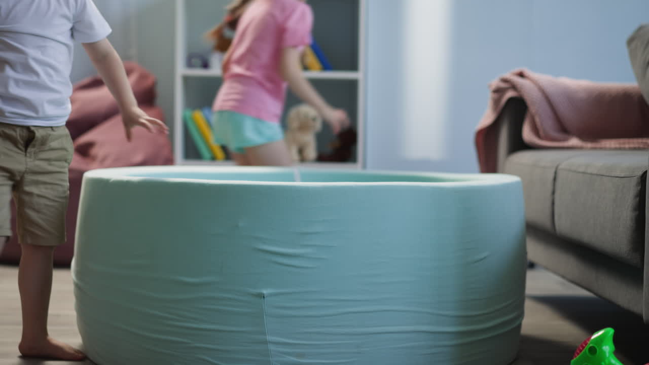 작은 형제 자매들은 공을 모아서 거실에서 수영장을 채운다.
