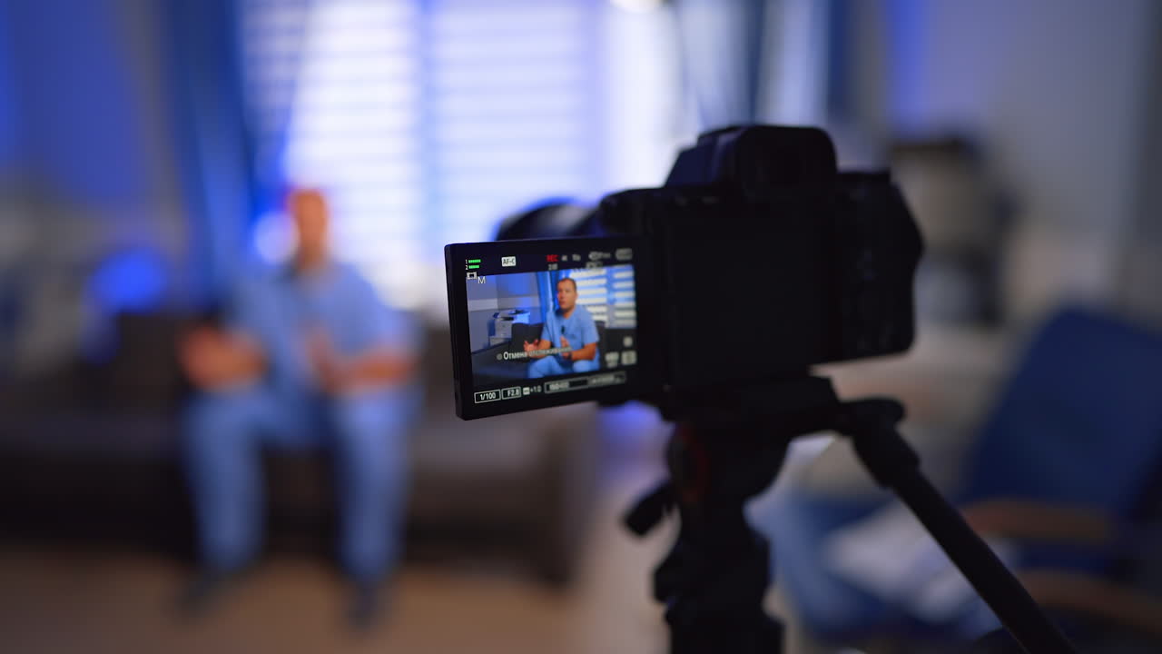 Man wearing blue uniform talking on the display of a modern camera. Close up. Vlogging concept. Selective focus