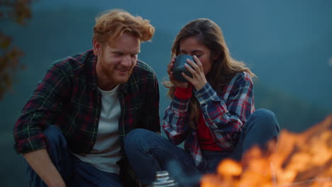 young couple rest outside on nature mountains. happy family talk chat by bonfire