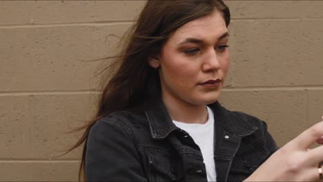 Steadicam-shot-of-a-beautiful,-young,-brunette-college-teenager-using-her-smart-phone-to-take-a-selfie-at-a-city-park