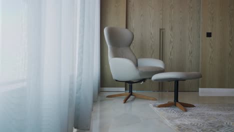 white armchair with stool at the corner of room