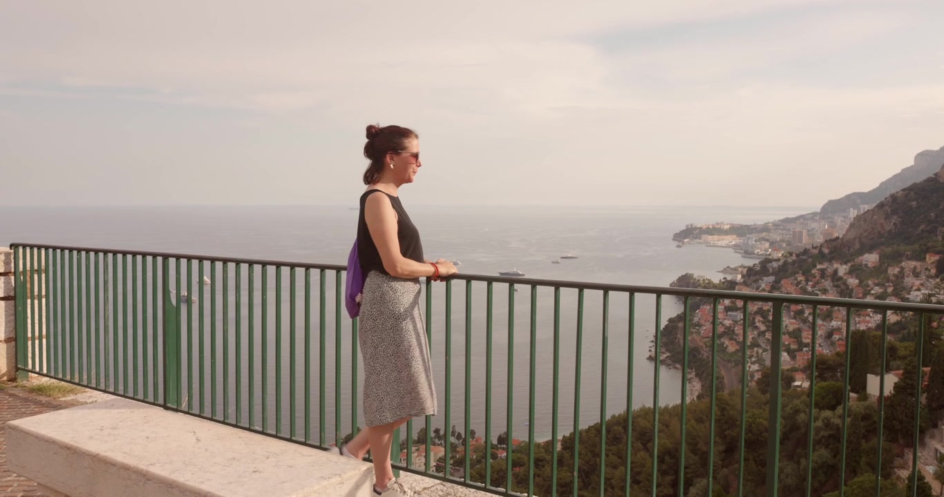 Woman enjoying a scenic panoramic view over the French Riviera from Roquebrune-Cap-Martin, with Monaco visible in the far background. Travel lifestyle, summer vacation, and coastal beauty in the South