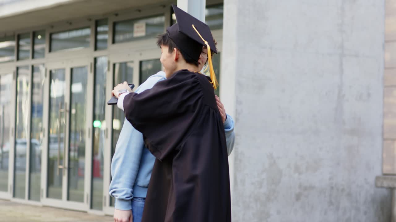 Diversi amici di sesso maschile salutano un laureato all'ingresso con una stretta di mano, un abbraccio e una chat al telefono, spazio per il testo