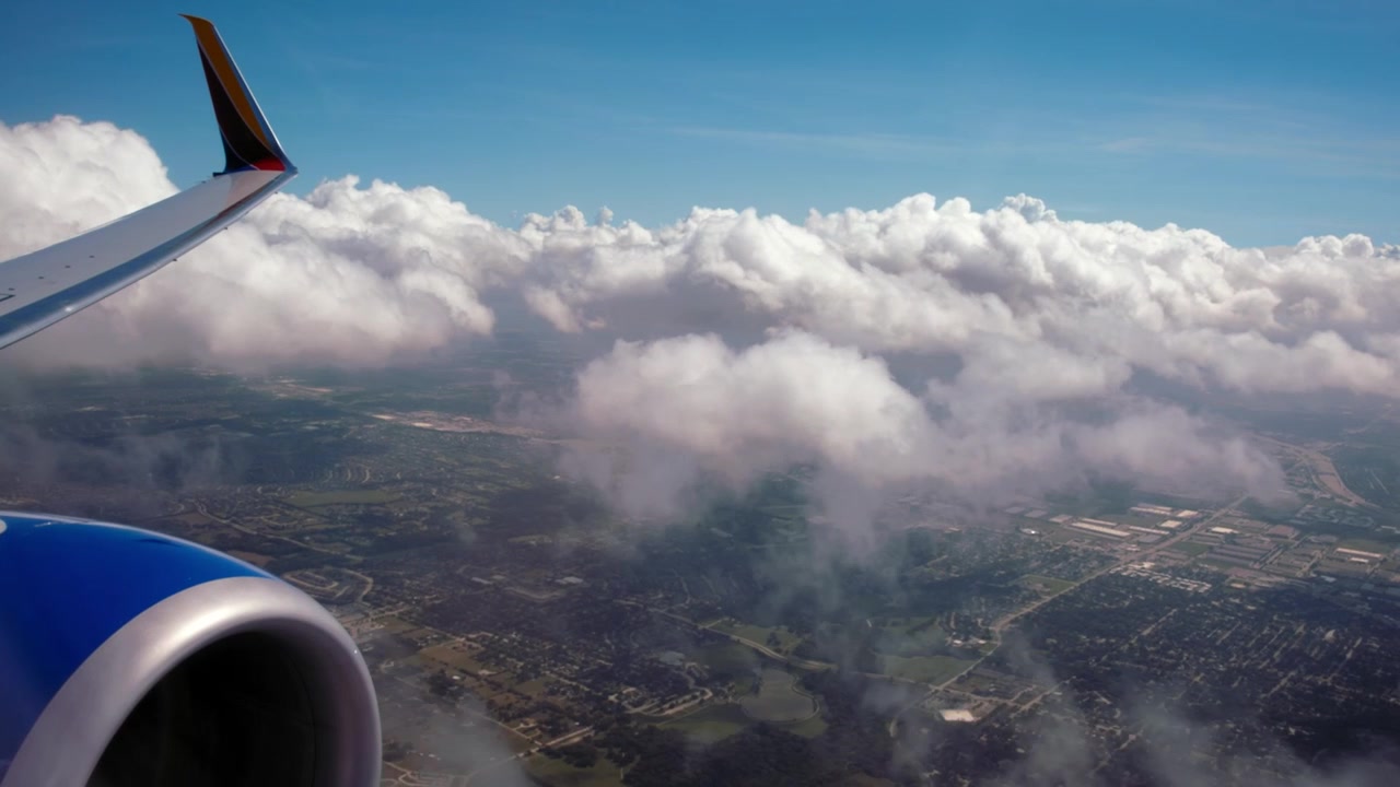Vista dalla parte anteriore dell'ala mentre un aereo vola basso sopra le nuvole e vira.