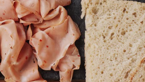 ham italian mordatella, man slices of traditional italian antipasti mortadella sausage on a wooden cutting board, close up macro of chicken or turkey jamon, fat breakfast dish.