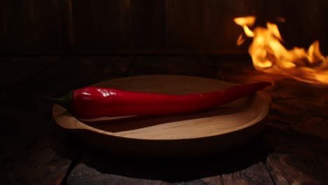 red chili pepper on wooden plate with fire