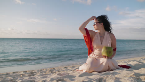 woman relaxing on a tropical beach with a coconut drink