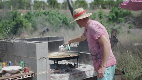 man cooking paella outdoors over an open fire barbecue