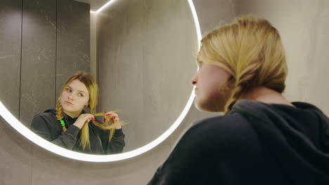 woman styling her hair in bathroom mirror