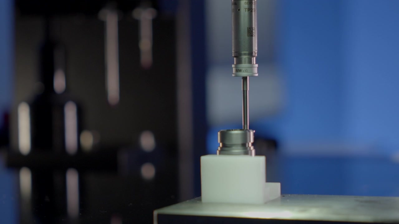 Sistema SmartScope automatizzato che preleva una sonda di misurazione di precisione per l'ispezione di componenti CNC in un ambiente di metrologia industriale.