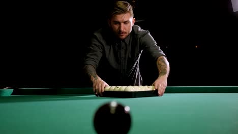 triangle of billiard balls. a man getting ready to start a game of billiards.