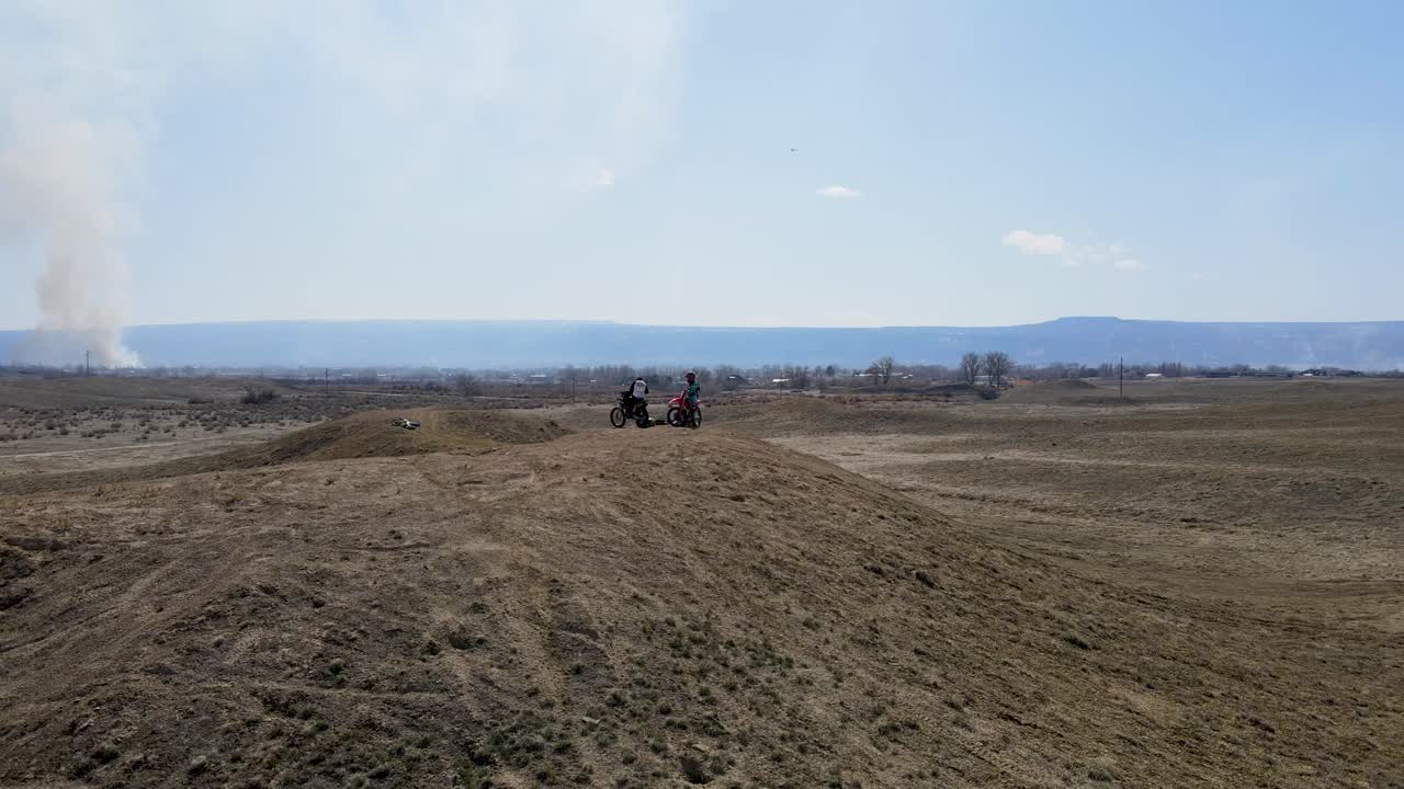 una espectacular y rápida toma de drone de dos pilotos de motocross preparándose para golpear un gran salto de colina, en el terreno desértico del área de grand valley ohv, ubicado en grand junction, colorado