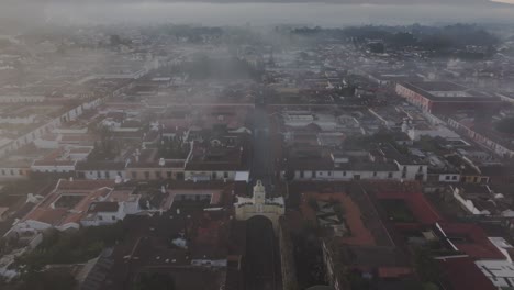 tilt up shot of santa catalina arch at antigua foggy sunrise, aerial