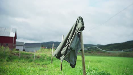 Chaqueta-Con-Capucha-Colgada-En-El-Poste-De-La-Cerca,-Soplada-Por-El-Viento-En-El-Campo