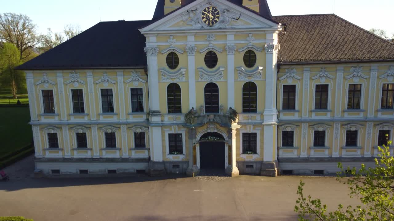 Aerial drone ascend along yellow and white front of Castle Kravare with autumn foliage, historic architecture in Czech Republic