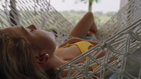 young woman in hammock swaying peacefully on lazy summer day enjoying vacation lifestyle at holiday resort