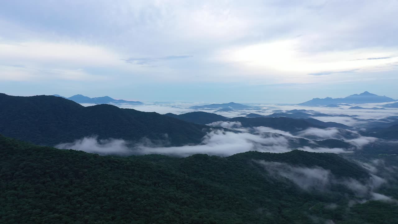 일출 때 구름 위의 높은 산의 아름다운 풍경을 패닝하는 드론