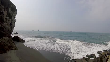 Waves-crashing-on-rocky-beach-with-ships-on-horizon-Kaohsiung-Taiwan