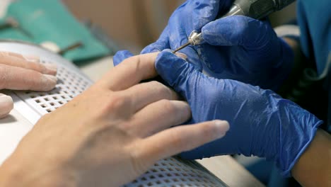 extremo primer plano, el maestro de la manicura trata las uñas de las mujeres antes de aplicar laca