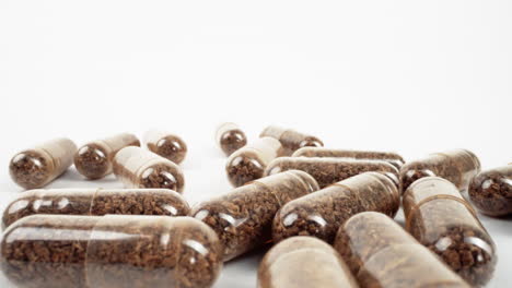 cápsulas transparentes dispersas con contenido herbal sobre fondo blanco