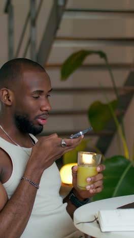 hombre usando teléfono móvil mientras bebe jugo en casa