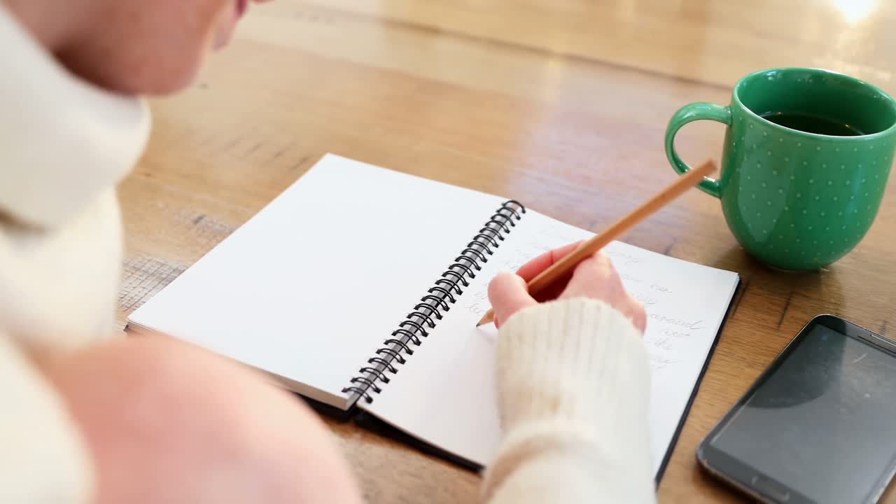 Close-up of woman writing in organizer while having coffee 4k