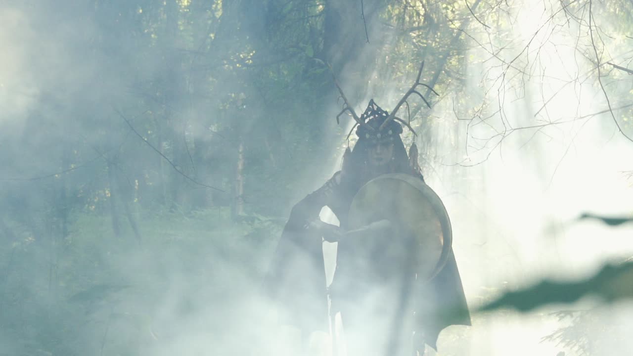 el chamán camina por el bosque mixto y toca el tambor