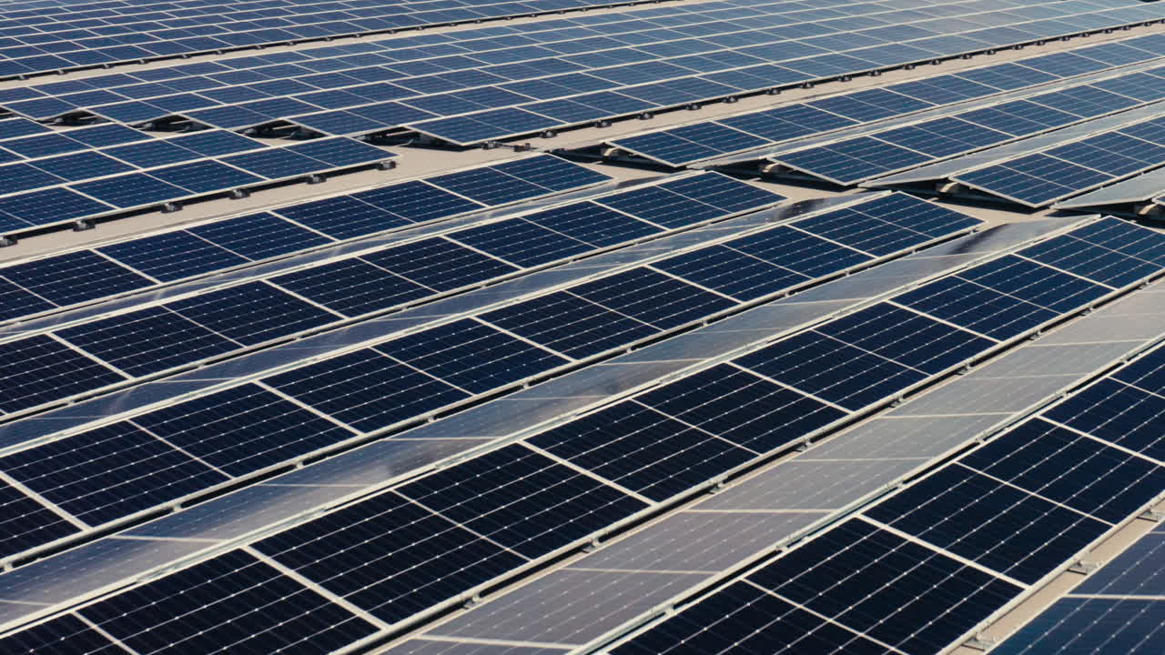 Una veduta aerea ravvicinata evidenzia file parallele di pannelli solari sui tetti, enfatizzando la produzione di energia pulita, la precisione tecnica e la geometria ripetitiva dell'infrastruttura rinnovabile.