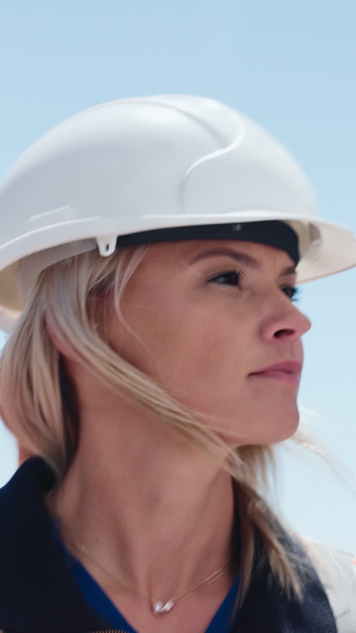 Primer plano de una ingeniera con casco mirando hacia arriba