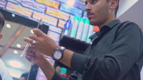 barber cuts man's hair with straight edge razor in a barbershop
