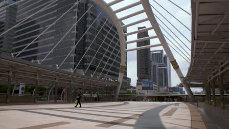 person walking on the empty sky bridge in chong nonsi, bangkok, thailand during covid-19 outbreak - wide shot