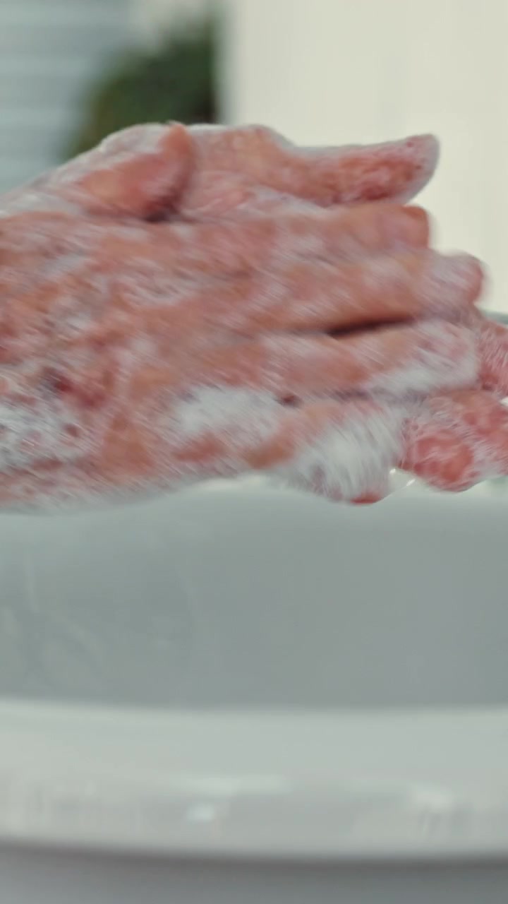 Persona anziana che si lava le mani con il sapone nel lavandino del bagno