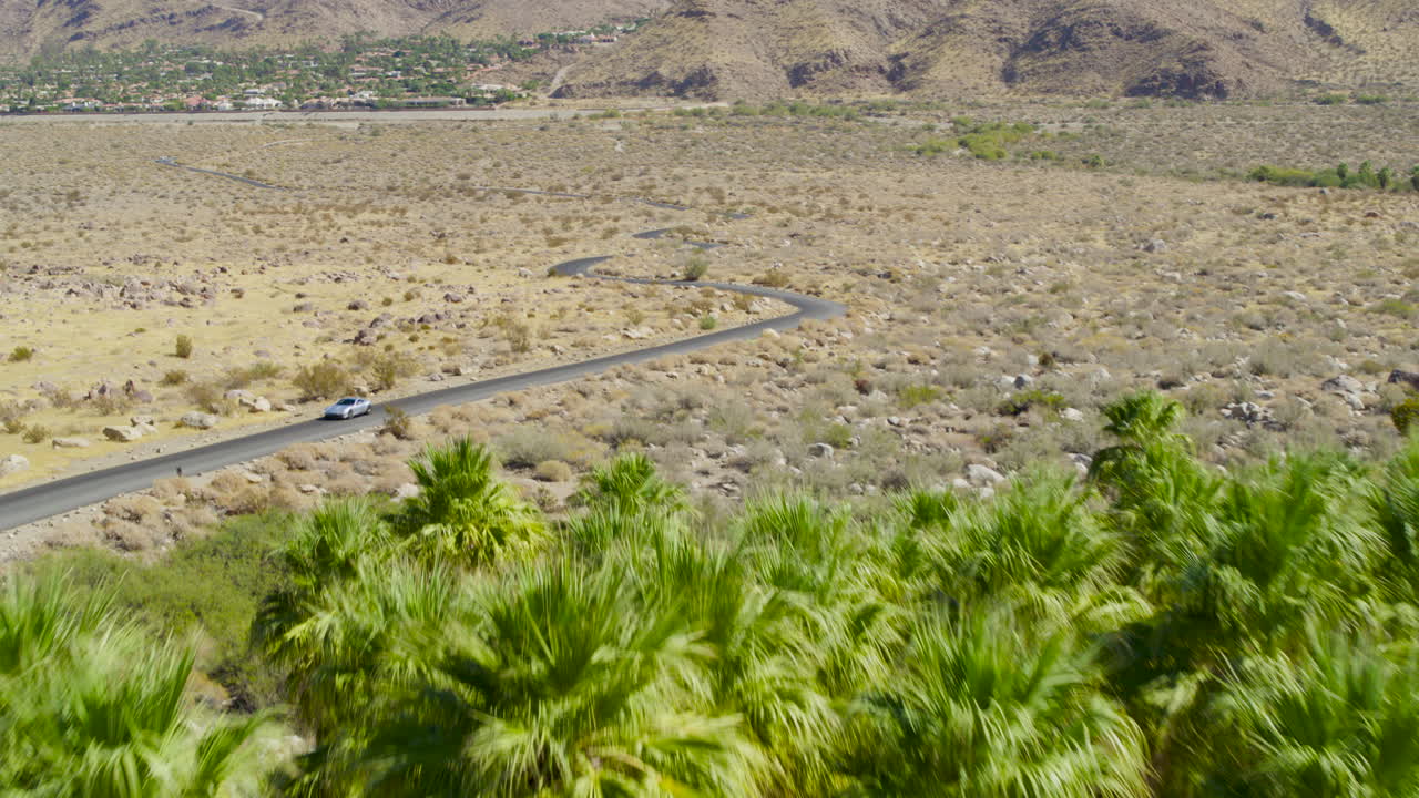 Palm Springs windmills spinning with the rugged San Jacinto Mountains rising behind them in California under a clear blue sky on a bright, sunny day. A vivid, modern-meets-nature scene
