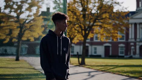 university student relaxing near a college building during a sunny autumn day, enjoying a break between classes while surrounded by vibrant fall leaves and serene nature