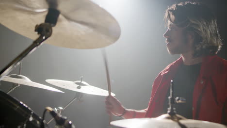 young male drummer playing drums at music studio