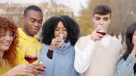 multi-ethnic friends standing in the street drinking wine